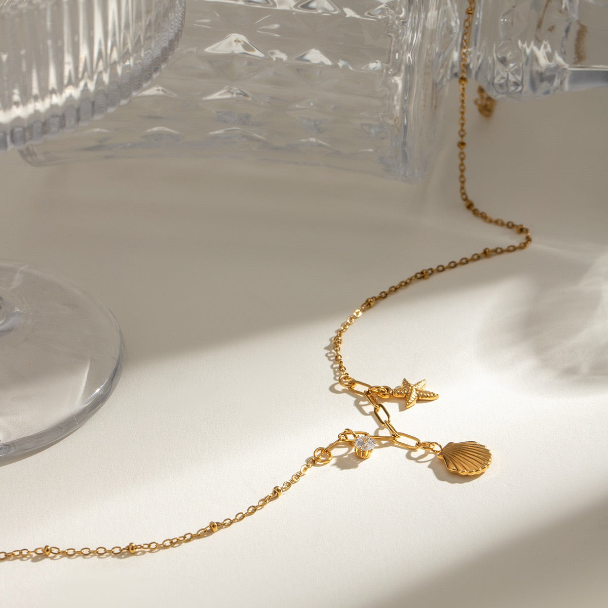 Close-up of starfish, seashell and zircon charms on a gold necklace